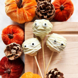 Cake pops deigned to look like mummies surrounded by miniature pumpkins and pinecones